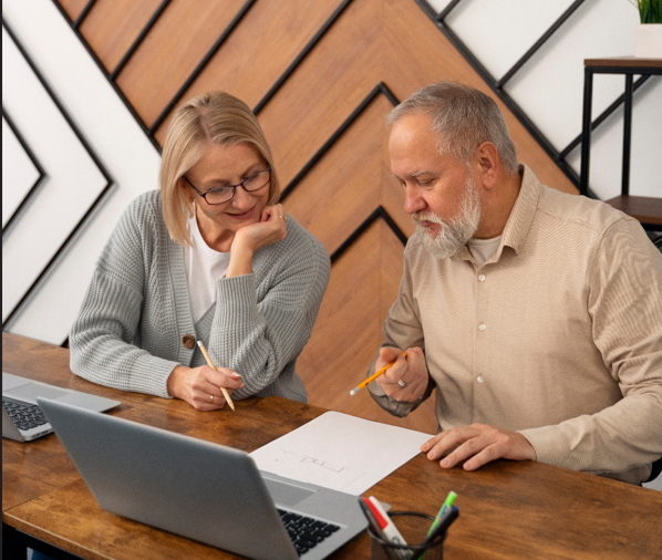 Woman in glasses reviewing financial paperwork, calculator, laptop at workspace